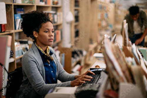 African American woman using desktop PC while working at bookstore.
