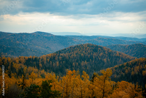 Panorama of the autumn forest against the blue sky with clouds.