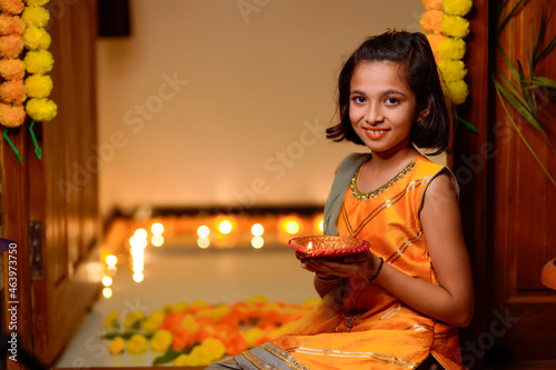 Cute Indian little girl holding diya or oil lamps for Diwali Celebration.