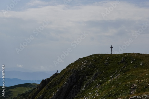 summit cross on a mountain and a standing hiker in austria