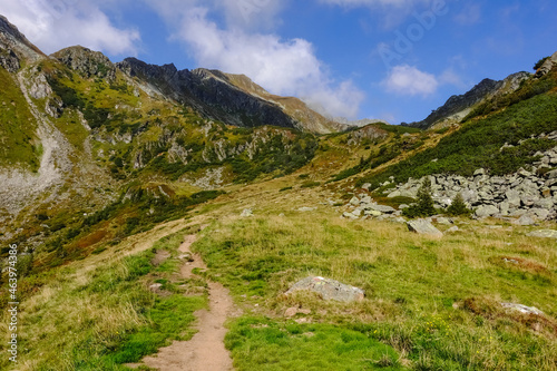 small path for hikers through green mountains with blue sky