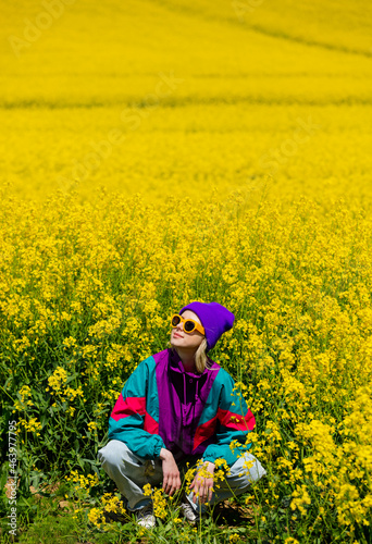 Stylish girl in 90s tracksuit in rapeseed field