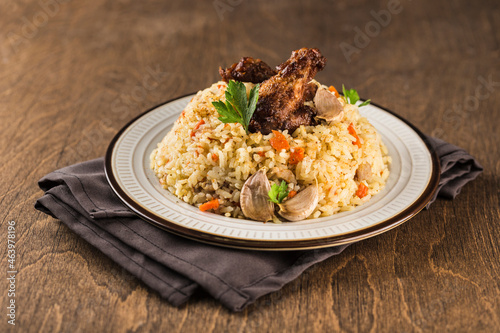 Pilaf with chicken drumstick in a light plate on a napkin