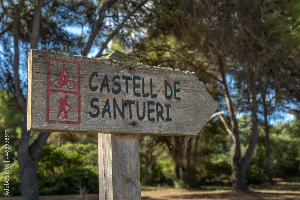 Fototapeta premium Close-up of the directional sign for the Santueri Castle, written in Catalan language, for hikers and walkers. Image of adventure tourism. Island of Mallorca, Spain