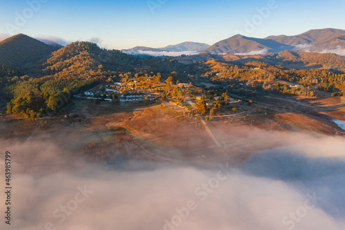 Aerial view of a caravan park on the shores of a mountain lake covered in fog