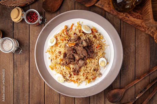 Uzbek national dish pilaf plov with rice and meat on wooden background