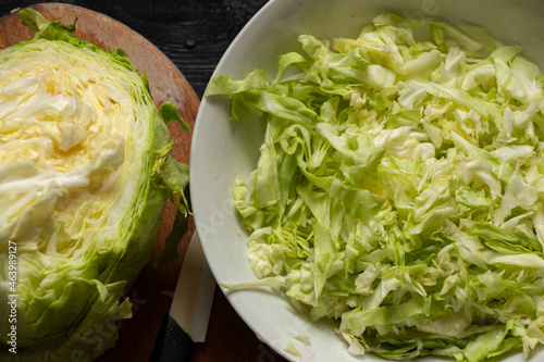 Bild auf Leinwand green young cabbage cut in a bowl and on a wooden board, cabbage salad on a wood