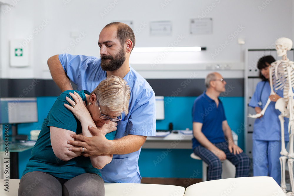 Chiropractic specialist cracking back and shoulder bones for retired woman at orthopedic consultation. Chiropractor giving assistance to elder patient for recovery and rehabilitation Chiropractic specialist cracking back and shoulder bones for retired woman at orthopedic consultation. Chiropractor giving assistance to elder patient for recovery and rehabilitation