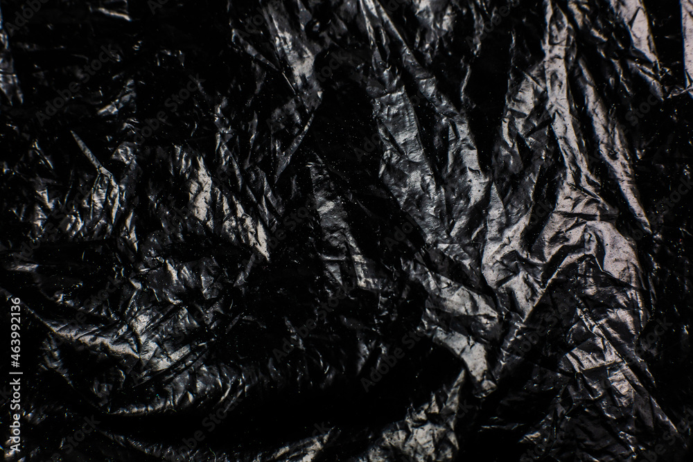 Fototapeta premium Crumpled Black Plastic Bag texture background. Glossy polyethylene overlay