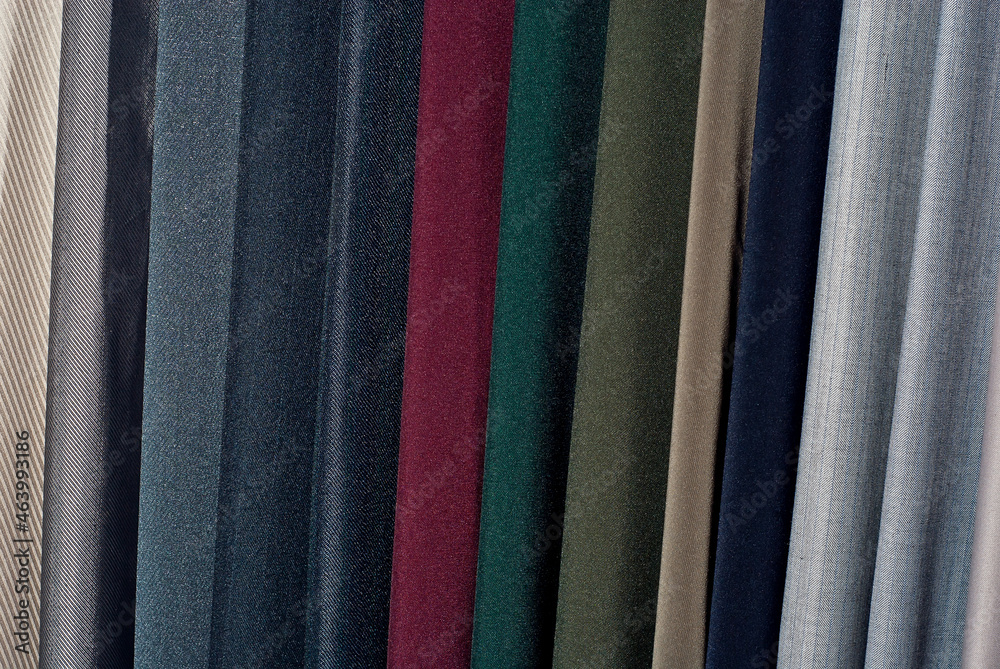 Texture of multicolored fabrics close up. Fabrics for sewing clothes hang in the store. Many fabrics of different materials, colors and textures.