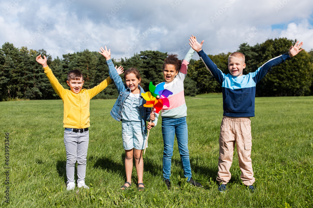 childhood, leisure and people concept - group of happy kids with pinwheel having fun at park childhood, leisure and people concept - group of happy kids with pinwheel having fun at park