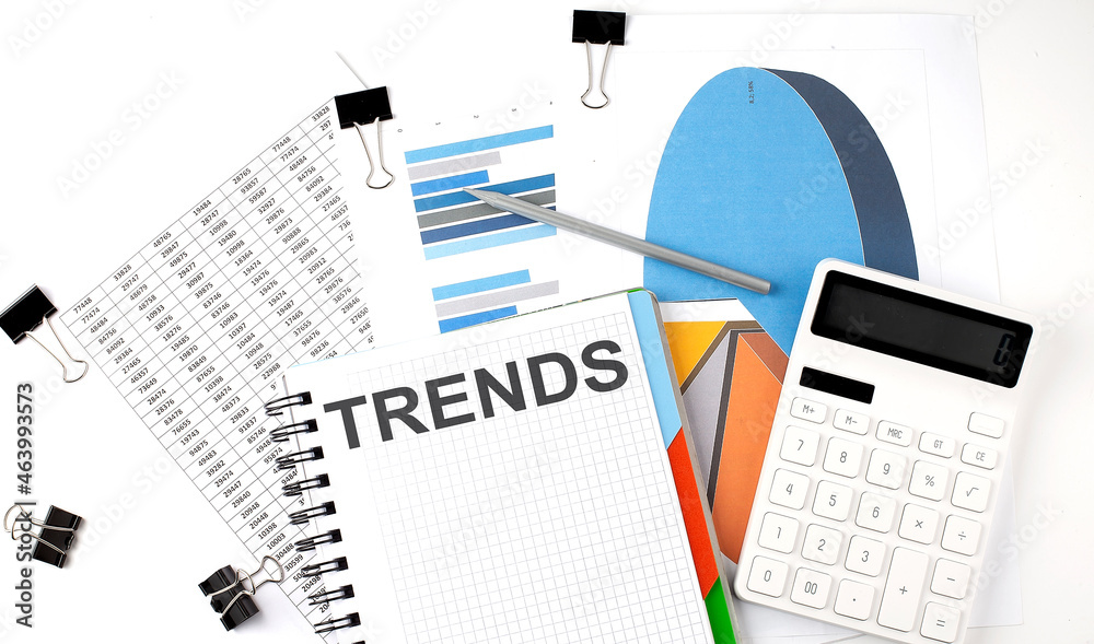 Text TRENDS on a notebook on the diagram and charts with calculator and pen Text TRENDS on a notebook on the diagram and charts with calculator and pen