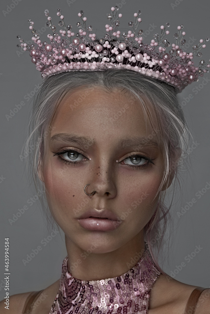 Close-up portrait of a girl. Concept. Nose piercing. Earring is a ring. Pink crown on the head. Princess.