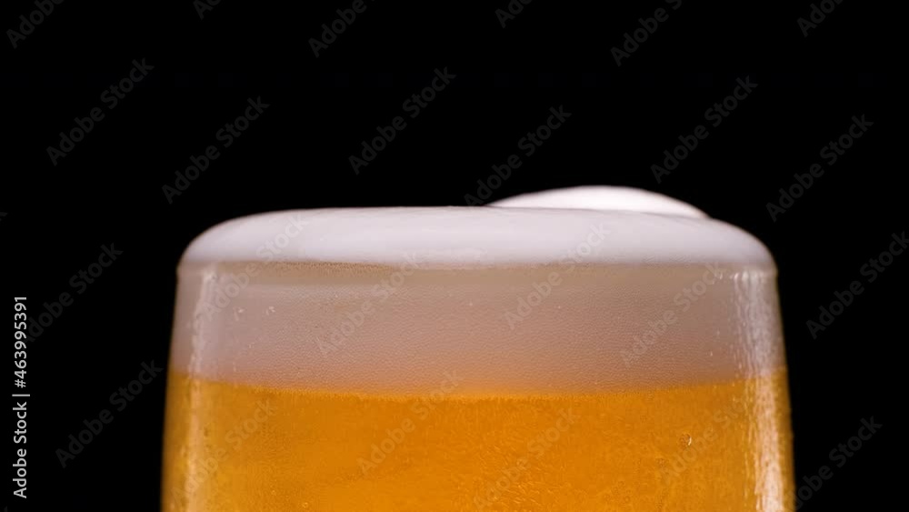 Slow motion. Lager beer pouring with bubbles and foam on black background Slow motion. Lager beer pouring with bubbles and foam on black background