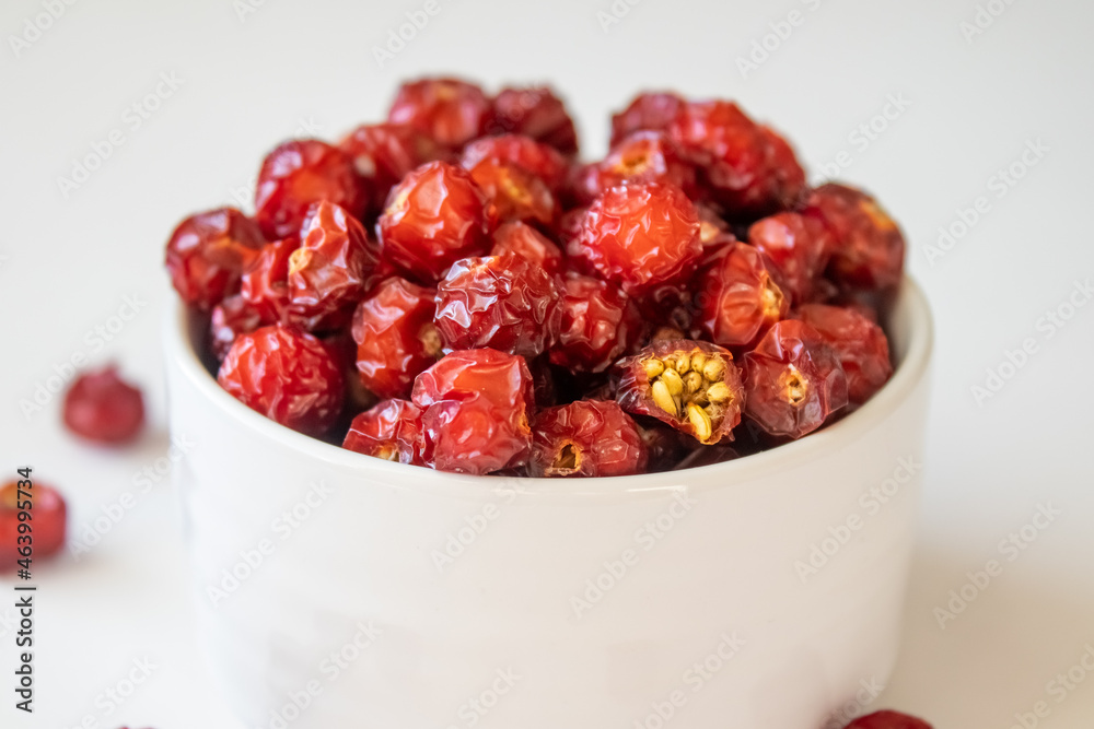 Sun-dried wild rose hip in a white bowl on white background Sun-dried wild rose hip in a white bowl on white background