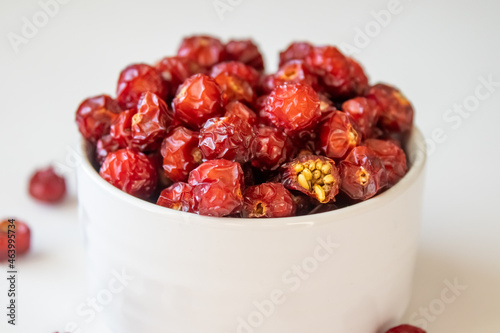 Sun-dried wild rose hip in a white bowl on white background