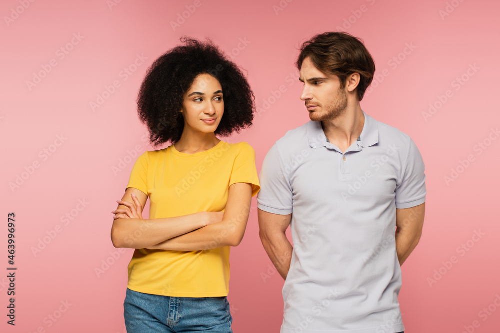 positive latin woman and offended man looking at each other isolated on pink. positive latin woman and offended man looking at each other isolated on pink.