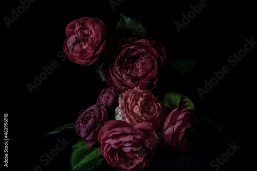 Moody flowers. bouquet of dark lilac roses on a black background. Blur and selective focus. Low key photo.