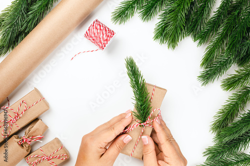 top view process of packaging and decorating Christmas gifts in frame of Christmas tree branches, craft paper. photo