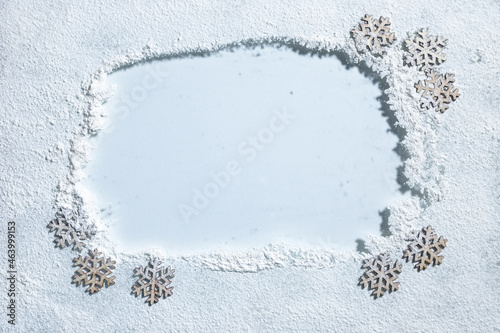 Wiped copy space on light clear glass surface framed by white snow and wooden decorative snowflakes.