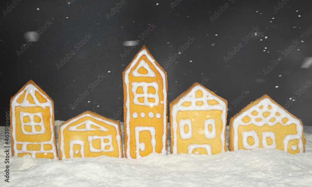 Christmas gingerbread houses stand under the snow at night
