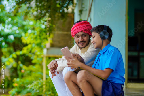 Indian school boy using smartphone and showing some detail to his father