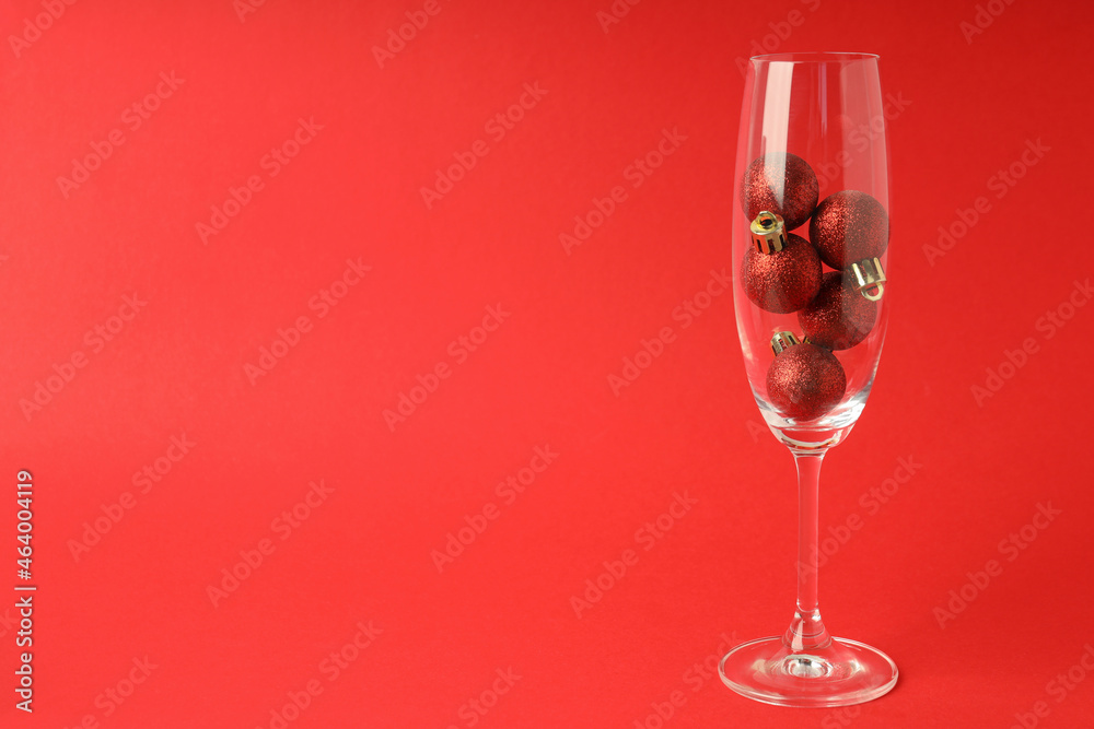 Champagne glass with baubles on red background Champagne glass with baubles on red background