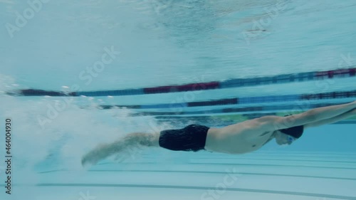 Underwater shot of swimmers in water immersion phase, sliding below the water surface and transition to swimming. photo