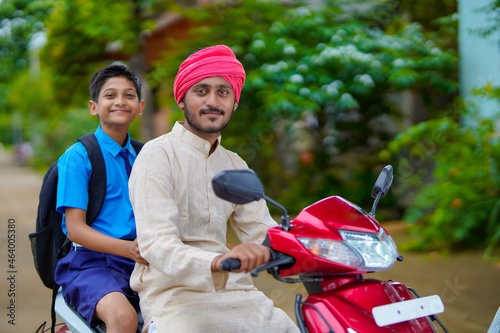 Young indian farmer dropping his child to school on bike