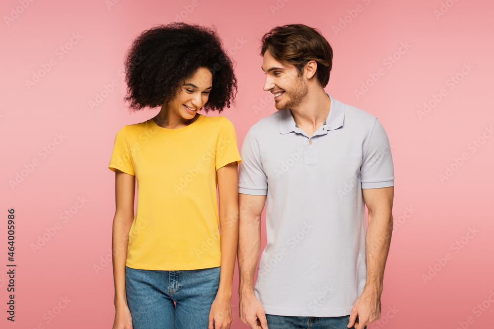 Fototapeta premium pretty latin woman and young man smiling while standing isolated on pink.