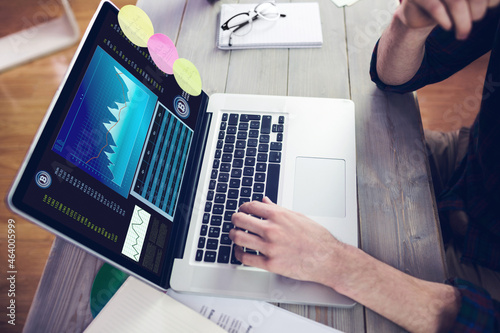 Hands of caucasian businessman sitting at desk, using laptop with statistical data on screen photo