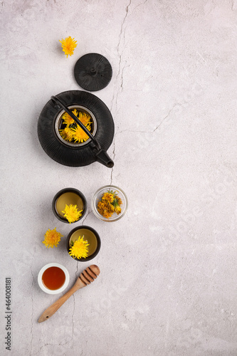 Healthy herbal dandelion tea and black teapot on stone background.