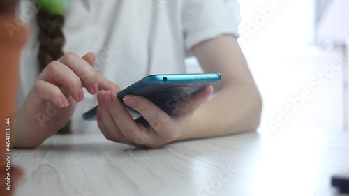 Young girl using mobile phone, checking fo the new notification and left smartphone on the wooden table