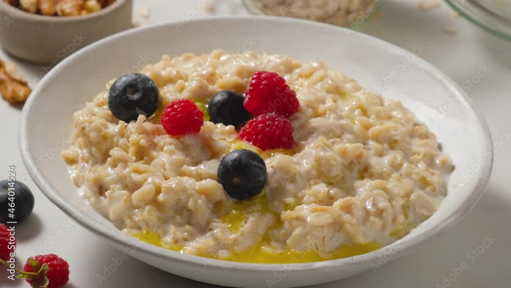 Adding fresh berries in oatmel porridge with butter in a plate. Healthy breakfast. close up. 4k video Adding fresh berries in oatmel porridge with butter in a plate. Healthy breakfast. close up. 4k video