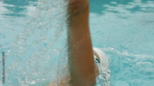 Tracking close-up shot of a young Caucasian female athlete swimming backstroke in the pool, arms movement, and easy breathing. photo