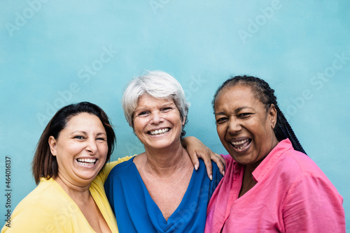 Fototapeta Multiracial senior women having fun hugging together outdoor - Focus on center w