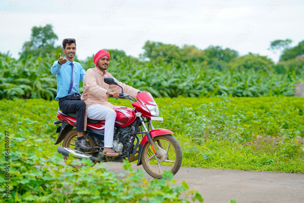 Indian agronomist going agriculture field with farmer on bike.
