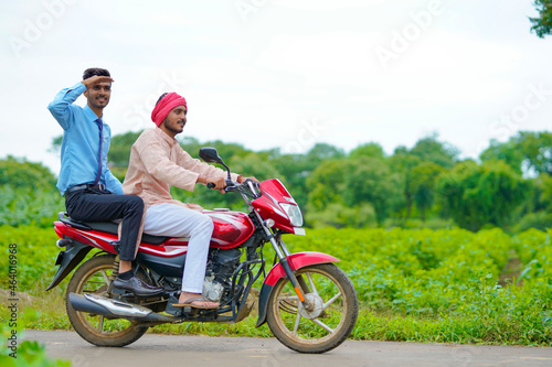 Indian agronomist going agriculture field with farmer on bike.