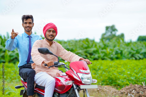 Indian agronomist going agriculture field with farmer on bike. photo