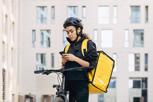 Bild auf Leinwand Woman courier with backpack checking information for delivery in the city