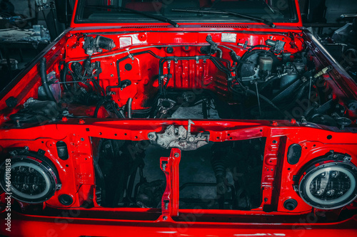 Photo of the open hood of a red car in the garage