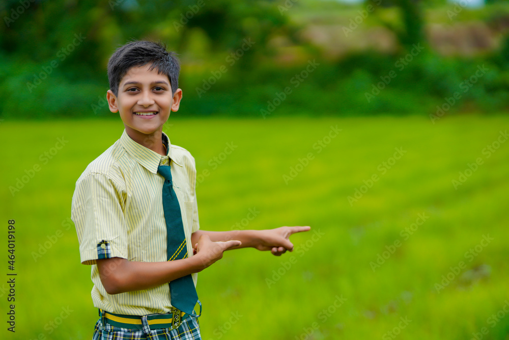 Indian school boy at green onion agriculture field.