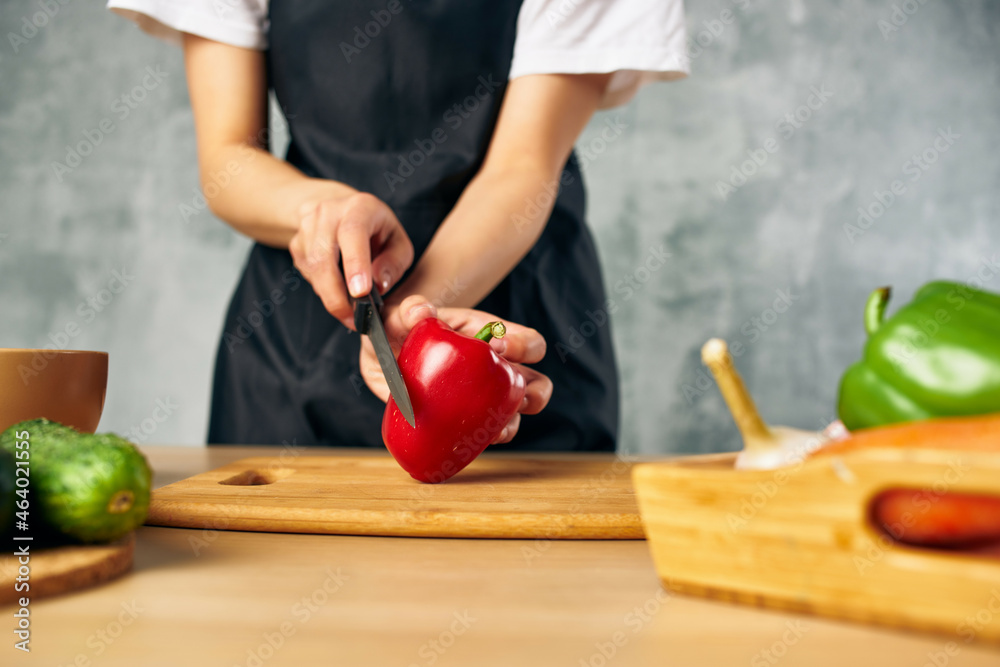 Woman in black apron on the kitchen cutting vegetables Woman in black apron on the kitchen cutting vegetables