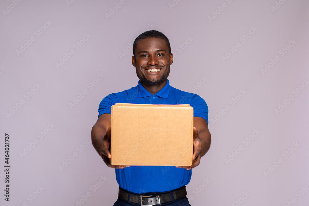 portrait of a black delivery worker holding forward a package