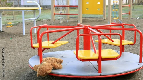 Teddy bear is spinning on a childrens carousel on an empty playground. The concept of Childhood, Toys, Growing Up