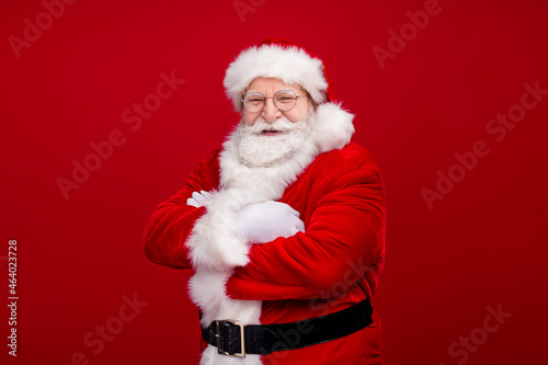 Photo of handsome confident man pensioner dressed santa claus costume taarms folded smiling isolated red color background © deagreez