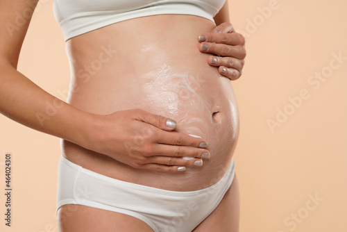 pregnant woman applying cosmetic cream on her belly to avoid stretch marks