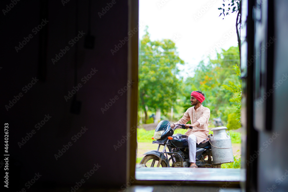 Rural scene : Indian milkman distribute milk on bike Rural scene : Indian milkman distribute milk on bike