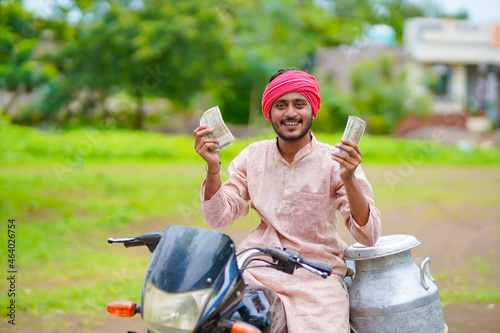 Foto Rural scene : Indian milkman sitting on bike and showing money