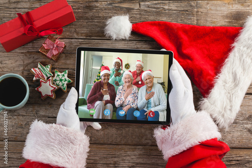 Caucasian santa claus on christmas laptop video call with diverse group of senior friends photo